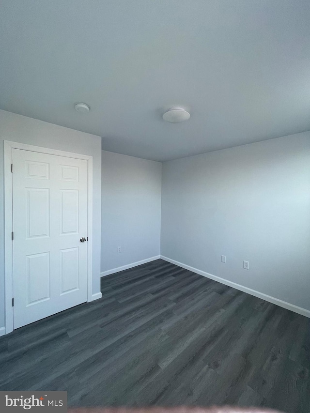 spare room with dark wood-style floors and baseboards