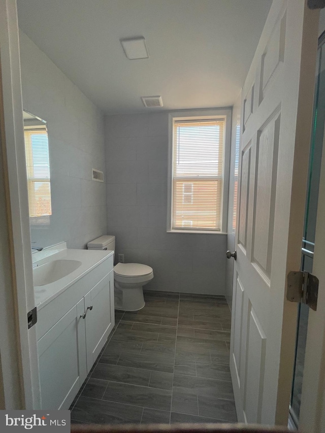 bathroom with visible vents, plenty of natural light, vanity, and toilet