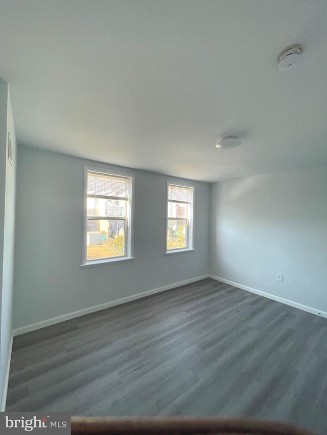 spare room with dark wood finished floors and baseboards