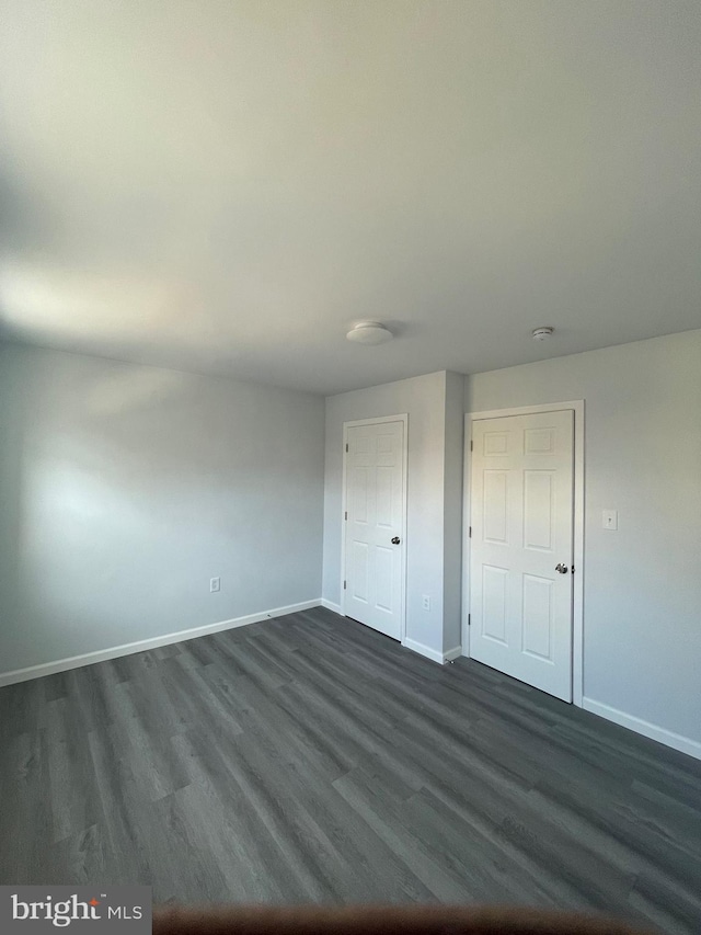 unfurnished bedroom with dark wood-style floors and baseboards