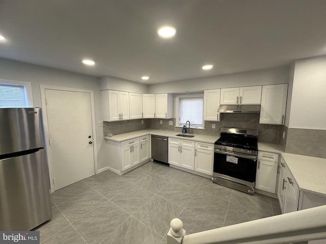 kitchen featuring light countertops, appliances with stainless steel finishes, white cabinetry, a sink, and under cabinet range hood