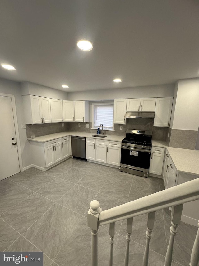 kitchen featuring under cabinet range hood, backsplash, stainless steel appliances, and light countertops