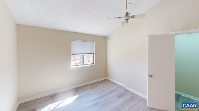 spare room with baseboards, visible vents, lofted ceiling, wood finished floors, and a textured ceiling