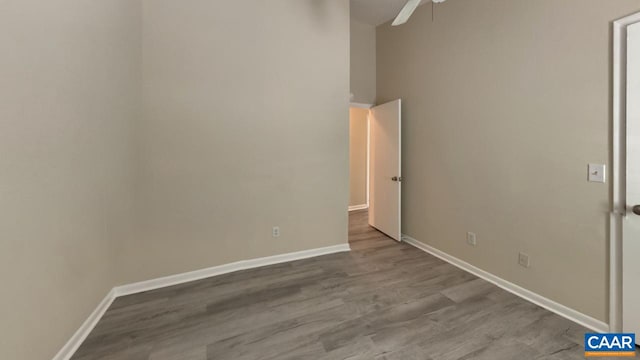 unfurnished bedroom with a towering ceiling, dark wood finished floors, a ceiling fan, and baseboards