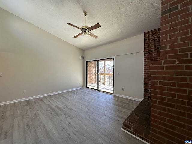 spare room with lofted ceiling, a textured ceiling, wood finished floors, and baseboards