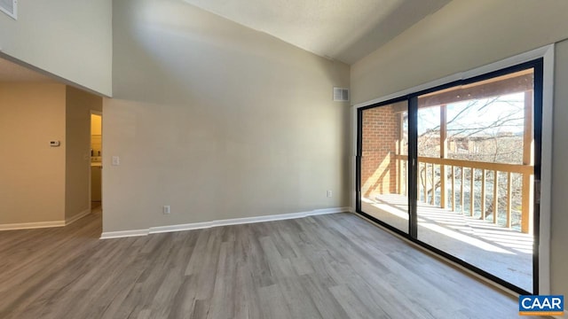 unfurnished room with high vaulted ceiling, visible vents, baseboards, and wood finished floors