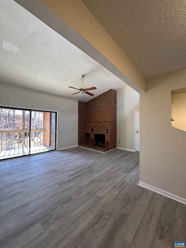 unfurnished living room with ceiling fan, a textured ceiling, a fireplace, wood finished floors, and baseboards