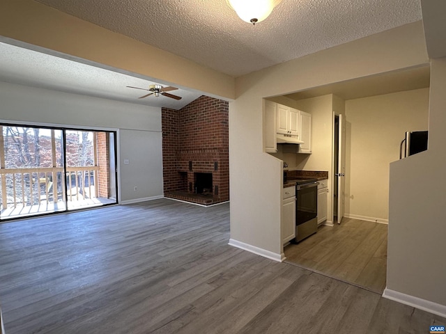 unfurnished living room featuring a textured ceiling, dark wood-style flooring, a ceiling fan, and baseboards