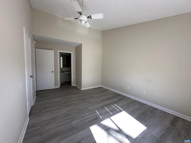 empty room with ceiling fan, a textured ceiling, baseboards, and wood finished floors