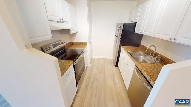 kitchen with under cabinet range hood, stainless steel appliances, a sink, white cabinetry, and light wood-type flooring