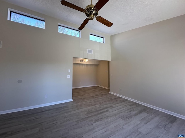 spare room with baseboards, visible vents, ceiling fan, dark wood-style flooring, and a textured ceiling