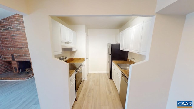 kitchen with light wood finished floors, appliances with stainless steel finishes, white cabinets, a sink, and under cabinet range hood