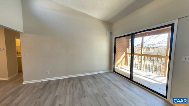 spare room featuring vaulted ceiling, wood finished floors, visible vents, and baseboards