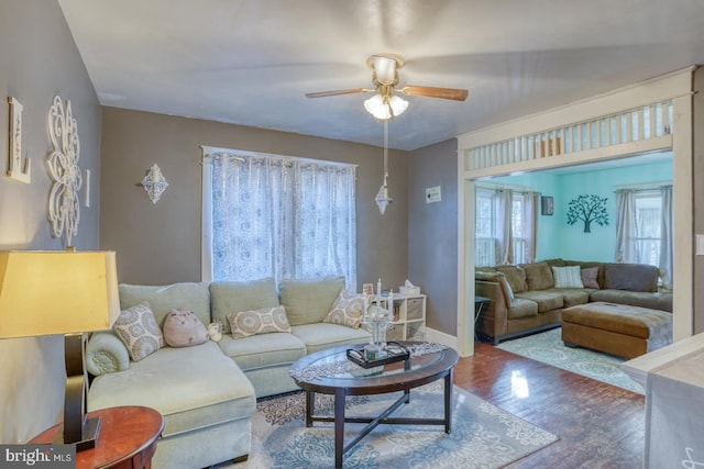 living area with baseboards, a ceiling fan, and wood finished floors