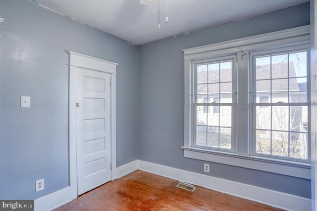 unfurnished room with baseboards, visible vents, and wood finished floors