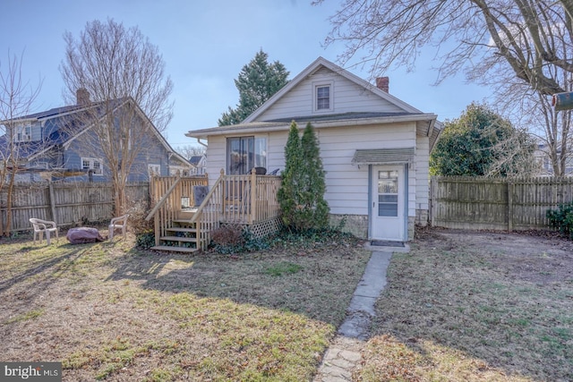 rear view of property with a chimney, a fenced backyard, a lawn, and a deck