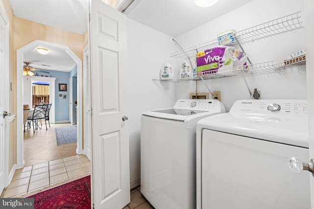 laundry area featuring arched walkways, ceiling fan, light tile patterned flooring, and washing machine and dryer