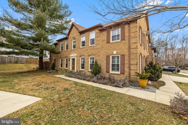 view of home's exterior with brick siding, fence, and a lawn