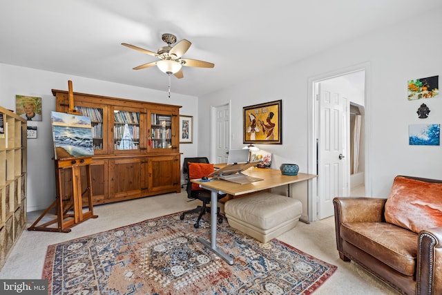 office space with a ceiling fan and light colored carpet