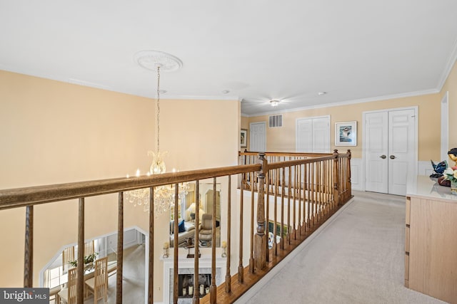 hall featuring light carpet, visible vents, ornamental molding, wainscoting, and an inviting chandelier