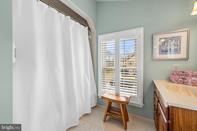 full bath featuring a shower with shower curtain, tile patterned flooring, baseboards, and vanity