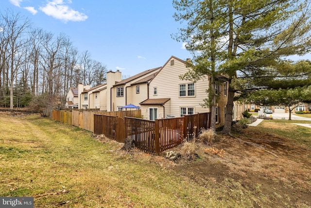 rear view of house with a lawn and fence