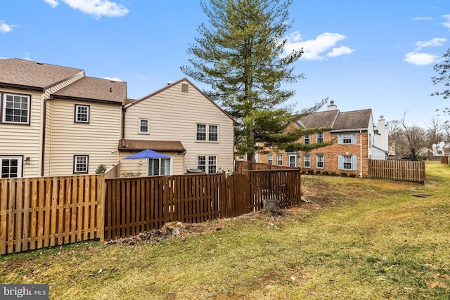 rear view of property with a lawn and fence