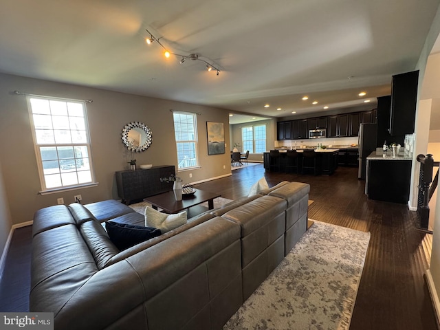 living room featuring dark wood-type flooring, recessed lighting, and baseboards