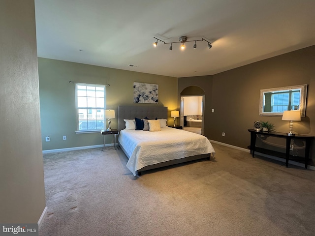 carpeted bedroom featuring arched walkways, visible vents, and baseboards