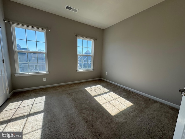 spare room with carpet flooring, visible vents, and baseboards