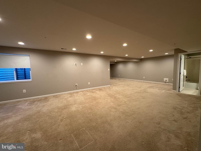 finished basement with light carpet, visible vents, baseboards, and recessed lighting