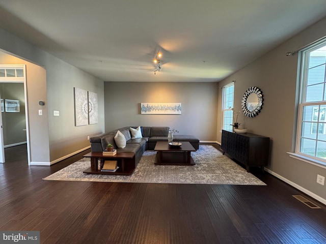 living area featuring dark wood-style floors, baseboards, visible vents, and rail lighting