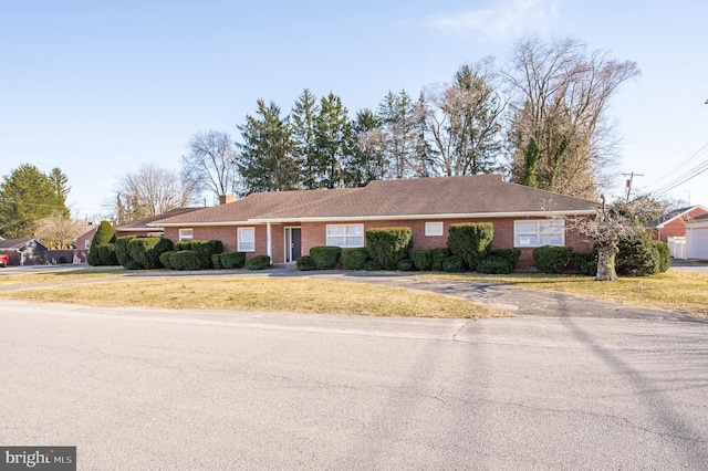 ranch-style home with a front yard, a chimney, and brick siding