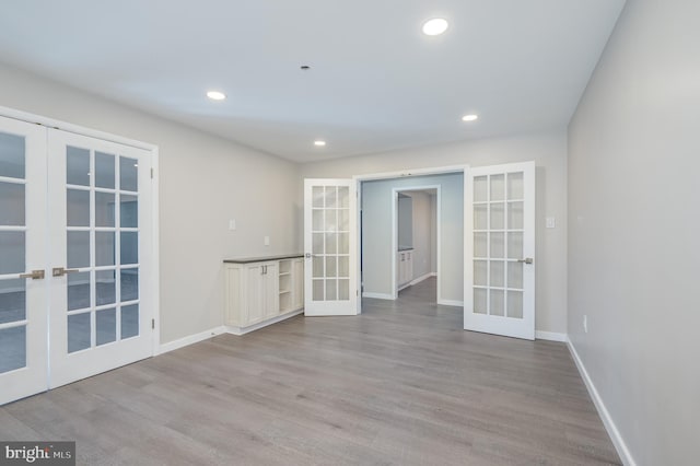 spare room featuring recessed lighting, french doors, baseboards, and wood finished floors