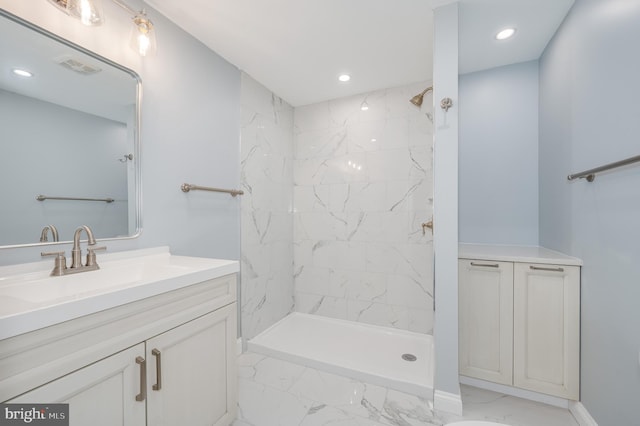 full bath featuring visible vents, marble finish floor, a tile shower, and vanity