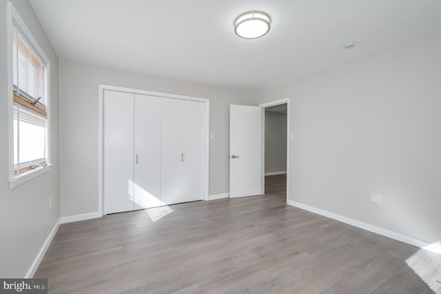 unfurnished bedroom with a closet, baseboards, and wood finished floors