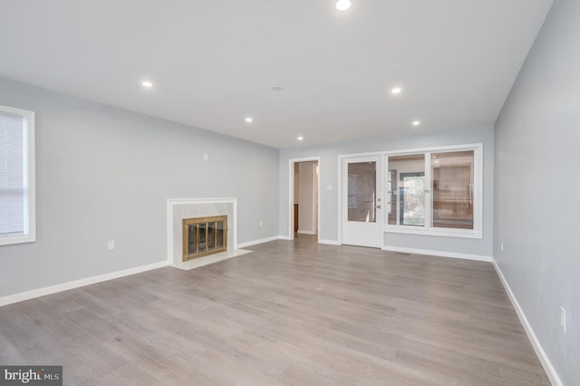 unfurnished living room featuring a premium fireplace, recessed lighting, wood finished floors, and baseboards