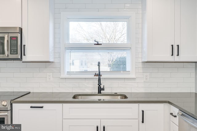 kitchen with stainless steel appliances, white cabinetry, a sink, and tasteful backsplash