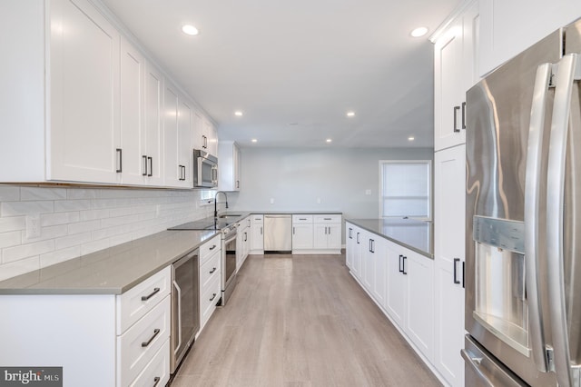 kitchen with light wood finished floors, white cabinets, decorative backsplash, wine cooler, and appliances with stainless steel finishes