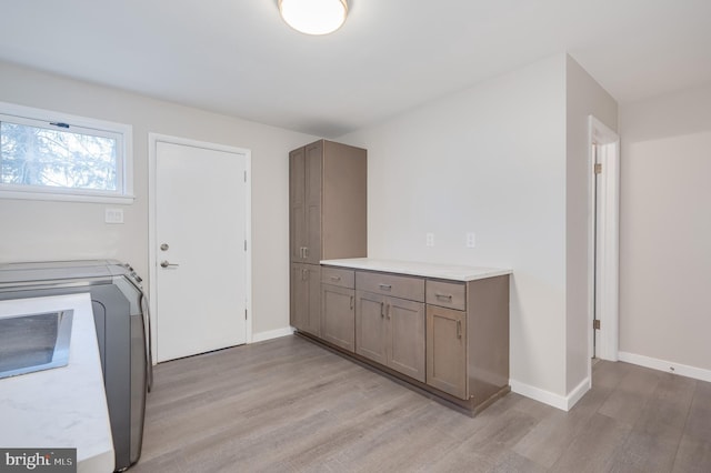 clothes washing area featuring laundry area, light wood finished floors, washer / clothes dryer, and baseboards