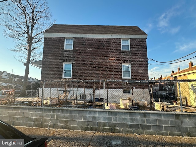 rear view of house with brick siding and fence