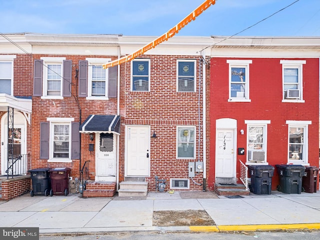 view of property with entry steps, cooling unit, and brick siding