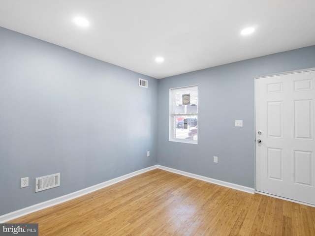 spare room featuring light wood finished floors, visible vents, and baseboards