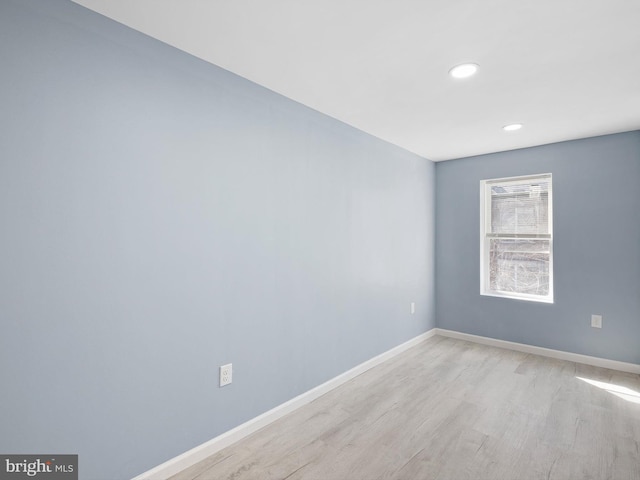 empty room featuring light wood finished floors, recessed lighting, and baseboards