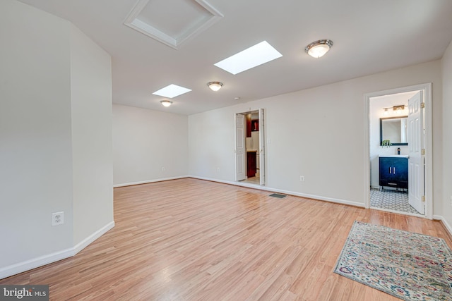 unfurnished room with baseboards, visible vents, and wood finished floors