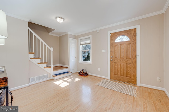 entryway featuring baseboards, visible vents, wood finished floors, stairs, and crown molding