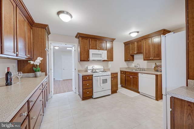 kitchen featuring brown cabinetry, white appliances, light countertops, and a sink