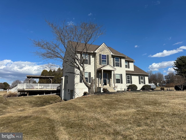 colonial inspired home with a front lawn and a wooden deck