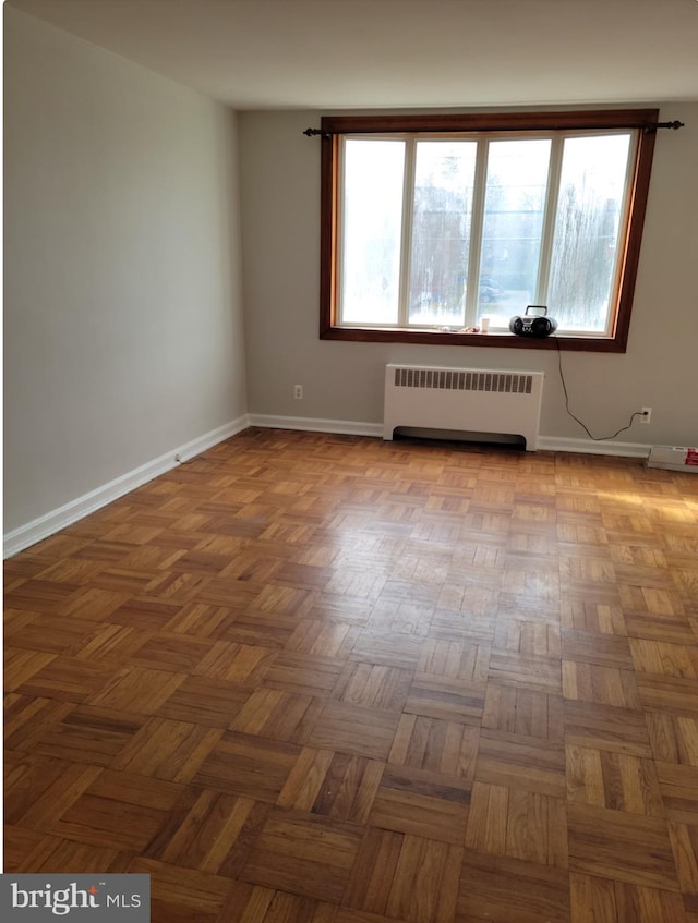 unfurnished room featuring baseboards and radiator