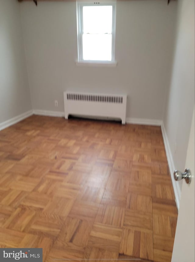 empty room with radiator heating unit and baseboards